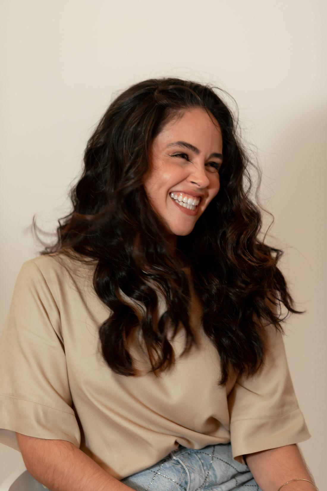 Smiling woman with long, voluminous, healthy wavy hair styled at Rare Salon, Dehradun